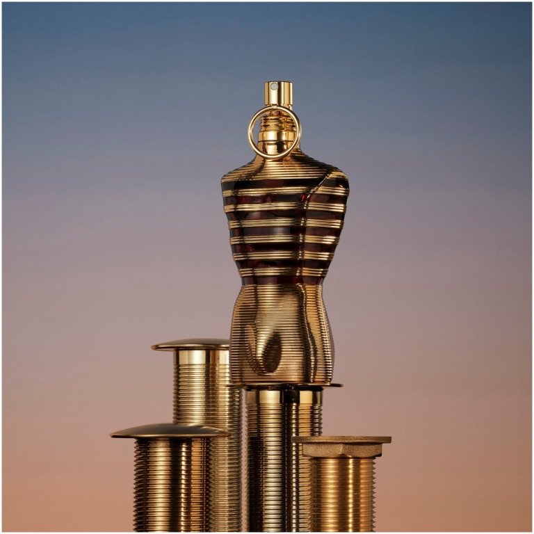 Jean Paul Gaultier Le Male Elixir, an intense woody aromatic amber men's perfume, in a gold torso-shaped bottle with fiery gold sailor stripes.